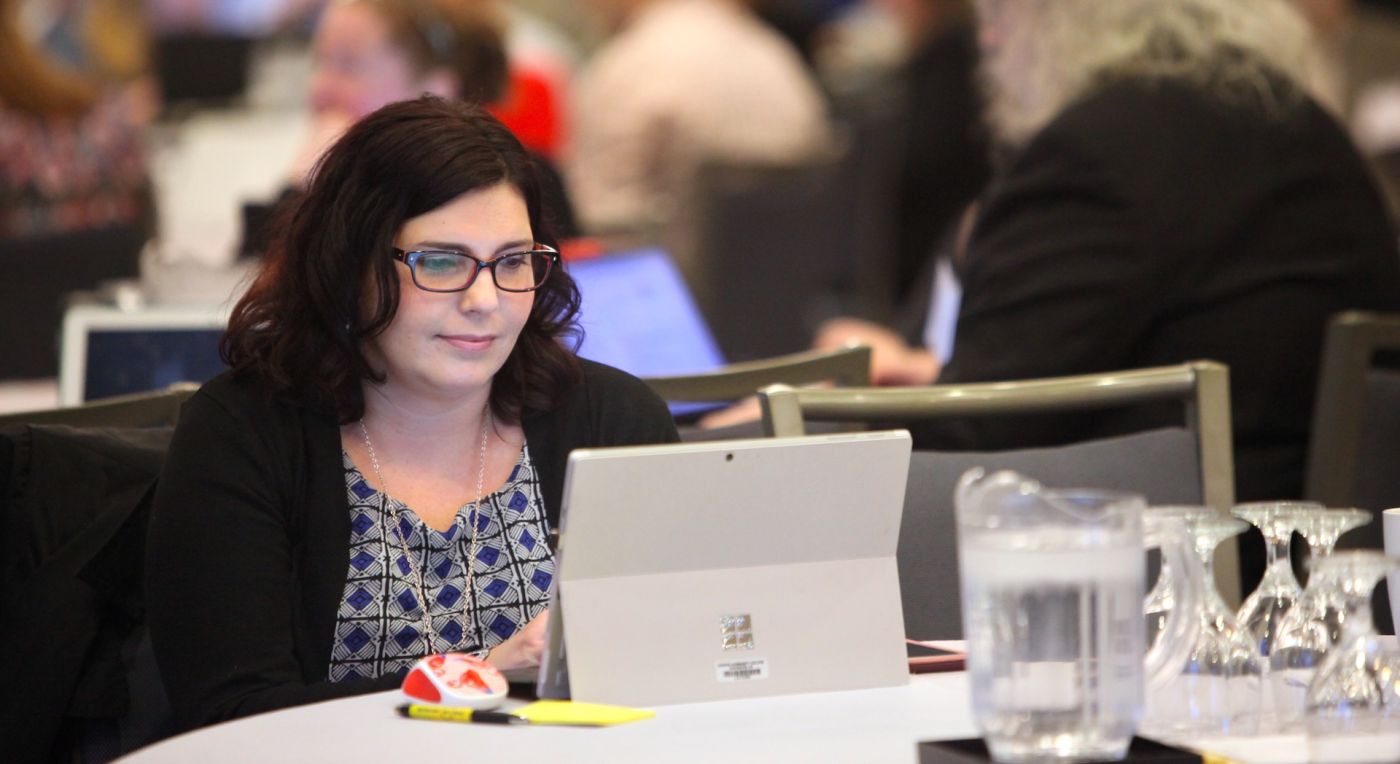 Educator sitting at table in front of laptop
