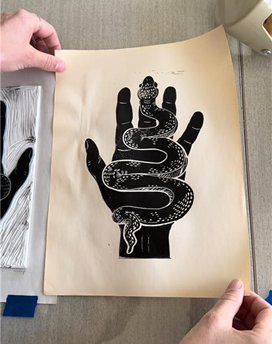 Linocut print of a hand holding a snake